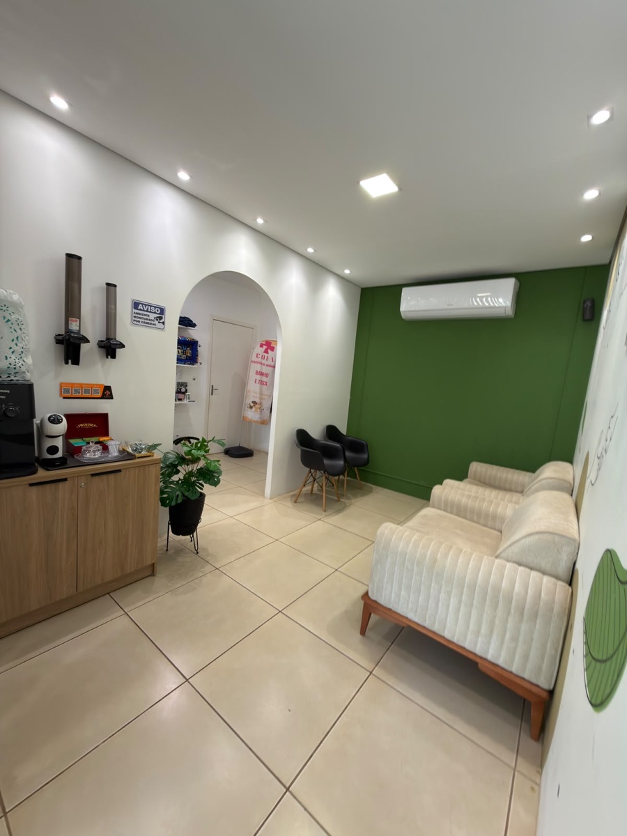 Área de espera da recepção da COEV, com sofá, poltronas, café disponível e parede verde
